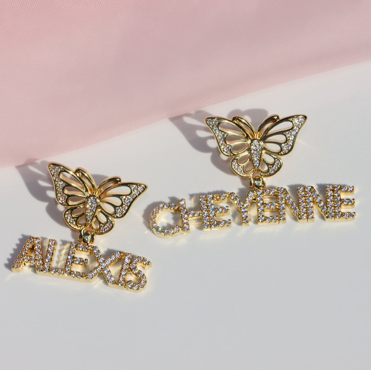 Butterfly-shaped earrings with personalized names on a pink and white background