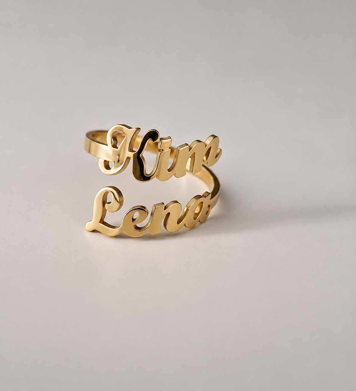 Gold ring with 'Kim Lena' engraving on a light gray background
