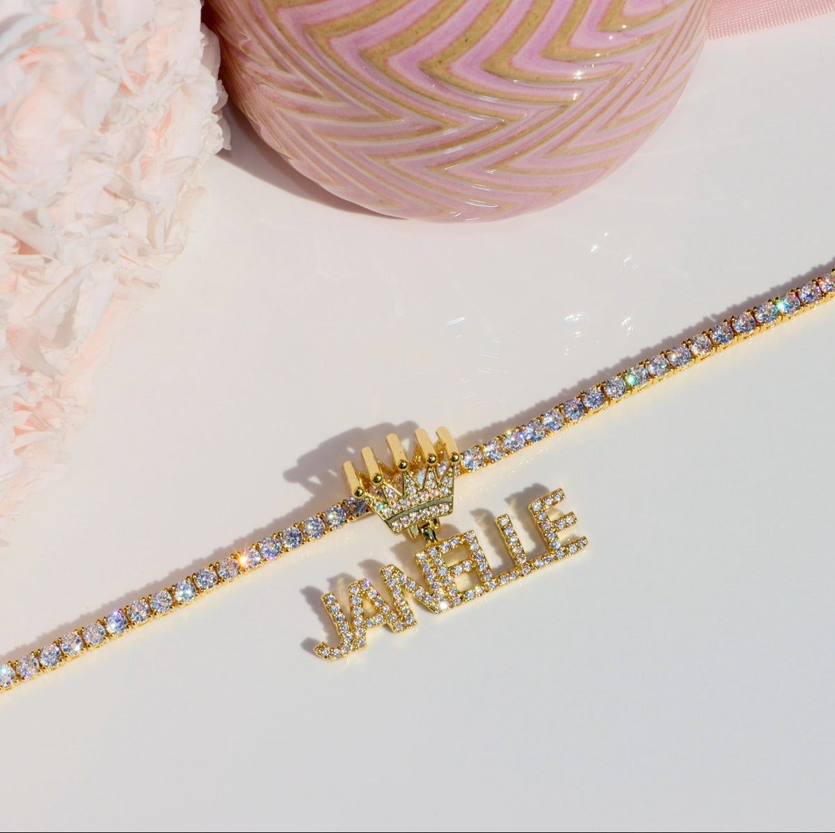 Gold bracelet with 'Janelle' on a light pink surface