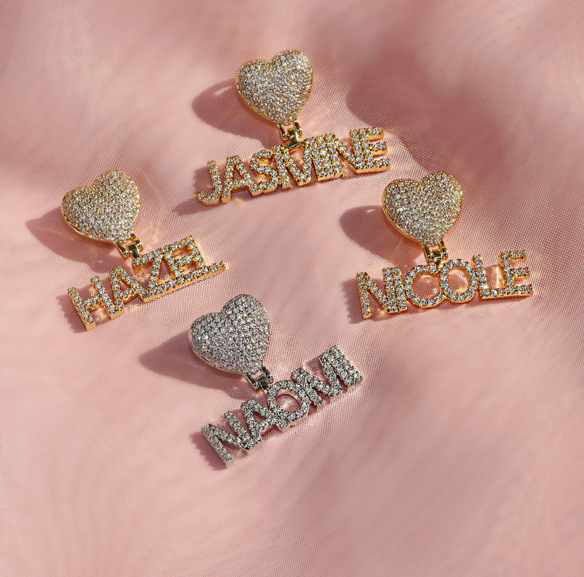 Heart-shaped name earrings on a pink fabric background