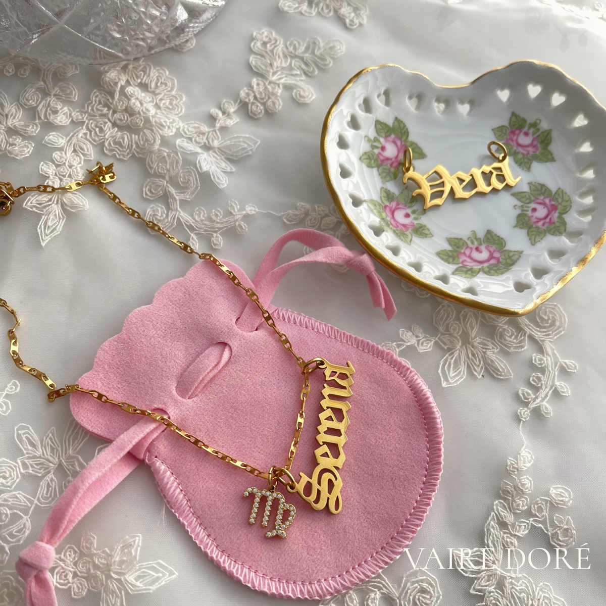 Gold nameplate necklaces displayed on a pink velvet pouch