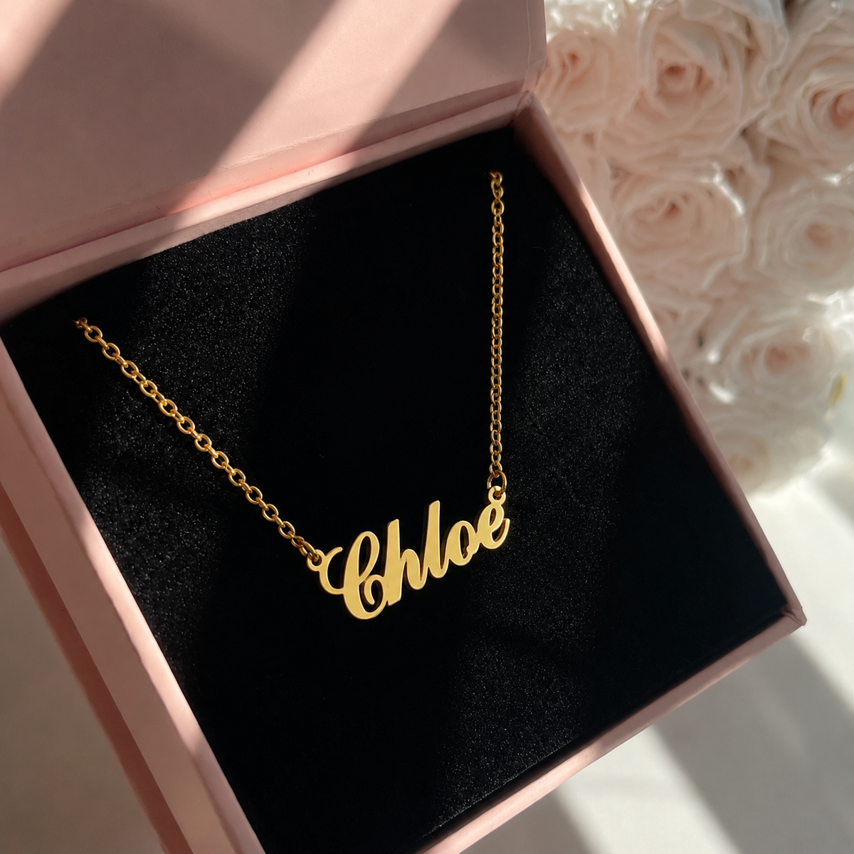 Gold 'Chloe' necklace in a pink box with floral background