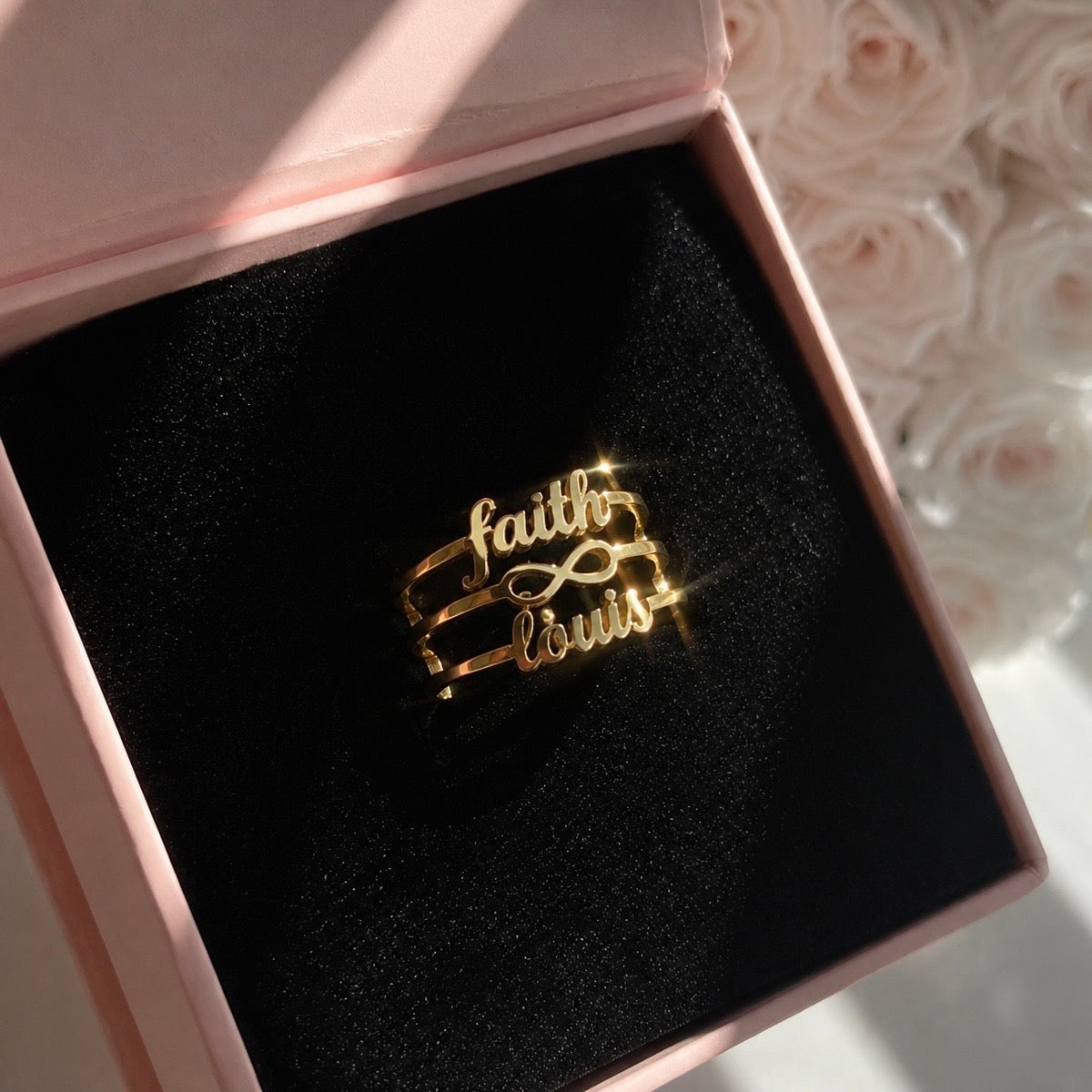 Gold 'faith' and 'love' brooch in a pink jewelry box with floral background