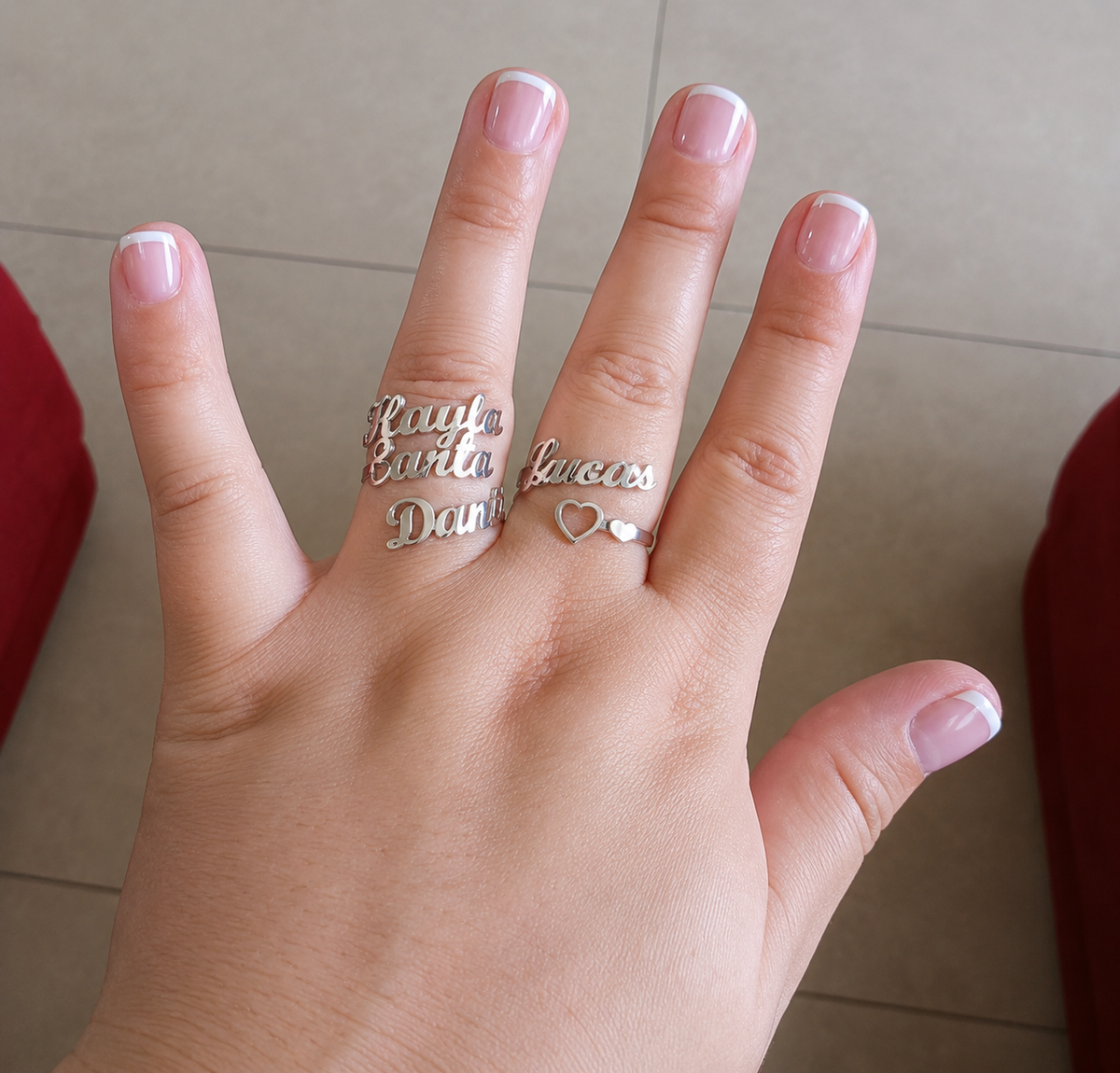 Hand wearing two silver rings with engraved text on a neutral background