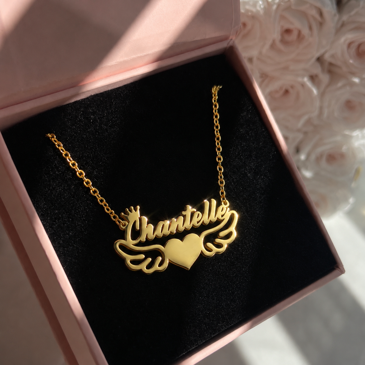 Gold necklace with 'Chantelle' in a pink box with roses in the background