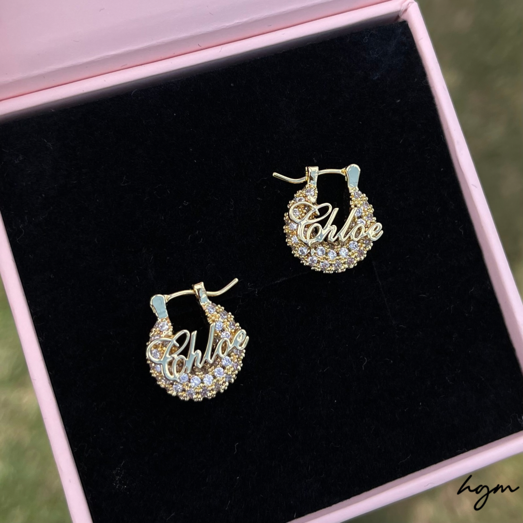 Gold hoop earrings with 'Chloe' inscription on black velvet in pink jewelry box